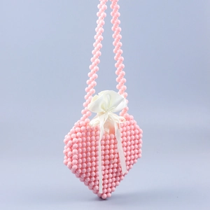 Close-up of a pink beaded heart bag with satin drawstring lining and ribbon bow