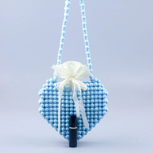 Macro detail of heart-shaped beaded handbag with white satin drawstring lining and bow