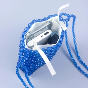 Blue handmade beaded crossbody bag with white drawstring liner showing daily storage capacity