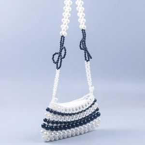 Detail of handmade pearl beaded handbag featuring black and white contrast with bow accents
