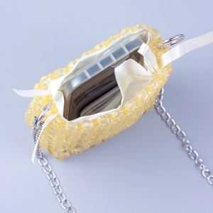 Detail view of yellow beaded phone bag with white drawstring liner and silver chain