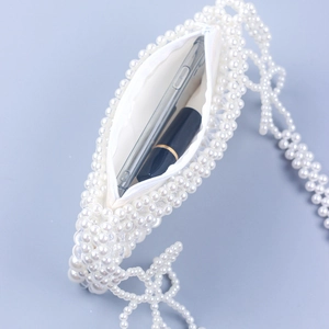 Detail showing the white pearl beaded bag interior with a phone and lipstick inside
