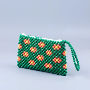 Detailed macro view of handmade green beaded clutch with floral patterns and zipper closure
