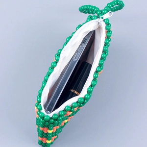 Green handmade beaded handbag with flower patterns holding a smartphone and lipstick