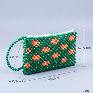 Detail of green handmade beaded clutch showing intricate woven floral patterns and zipper