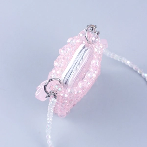 Detail of pink beaded mini bag with white strap holding wireless earbuds case