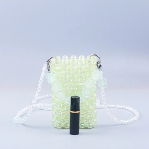 Mini light green beaded crossbody bag with heart charms and a lipstick for size comparison