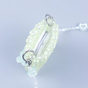 Detail of light green beaded mini bag with white heart charm for wireless earphones