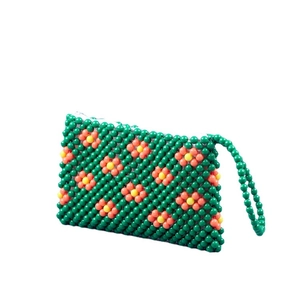 Handmade green beaded handbag with orange floral patterns and a secure white zipper closure