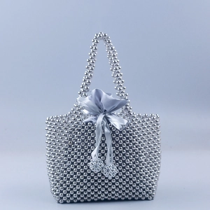 Détail d'un sac à main fait main en perles argentées avec doublure en satin gris à cordon