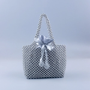 Détail du sac à main en perles argentées avec doublure en soie grise et ruban de satin