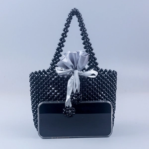 Détail du sac à main en perles montrant des perles noires et un sac intérieur en satin