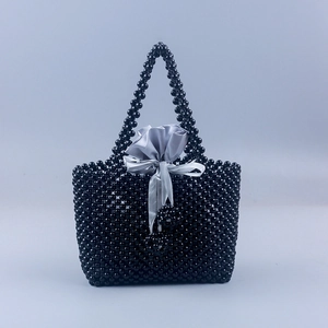 Détail du sac à main noir perlé à la main avec pochette en satin gris et nœud décoratif