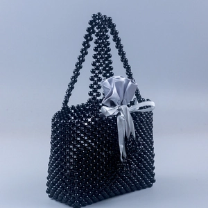 Détail du sac à main noir perlé avec pochette intérieure en satin gris et nœud élégant