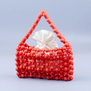 Detail of orange matte beaded handbag with a white satin drawstring inner pouch