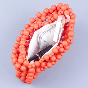 Macro view of bright orange beaded handbag showing white fabric lining and interior storage