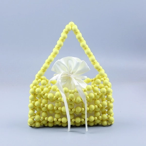 Detailed view of yellow beaded handbag with a white satin drawstring lining pouch