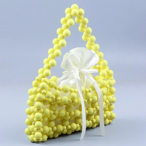 Detailed texture of yellow beaded woven handbag with white drawstring inner pouch