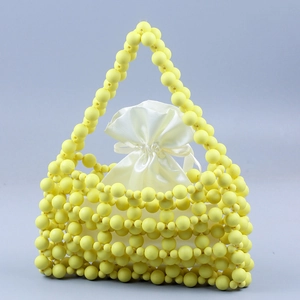 Detail of yellow beaded handbag with white satin drawstring pouch and frosted beads