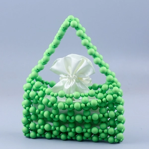 Detail of green beaded woven handbag with smooth white satin drawstring pouch