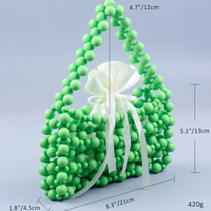 Detailed view of handmade green beaded bag with size dimensions and white satin pouch