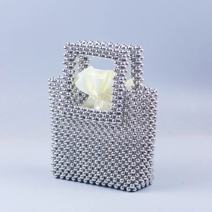 Close-up of handmade silver beaded handbag with square weave and white satin drawstring liner