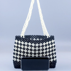 Handmade black and white beaded tote bag with clover pattern and phone for size reference