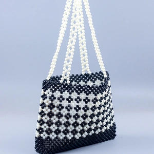 Detail of handmade woven beaded shoulder bag featuring black and white floral patterns