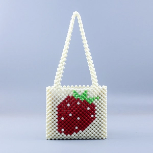 Close-up of handmade beaded handbag featuring pearl beads and a red strawberry motif