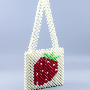 Detailed close-up of handmade beaded bag featuring strawberry pattern and white pearl beads