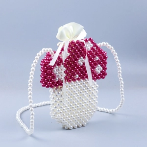 Detail of handmade mushroom pearl bag showing red and white beaded texture and drawstring
