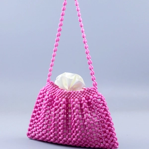 Close-up of pink handmade beaded handbag with white satin drawstring liner bag