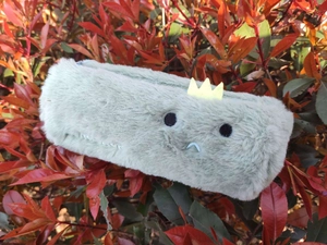 Detailed macro view of soft plush stationery pouch with embroidered face and crown