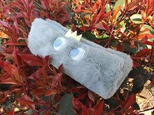 Close-up of cyan plush pencil case featuring a yellow crown and embroidered eyes