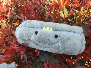 Macro detail of plush green dinosaur pencil case with soft texture and yellow crown