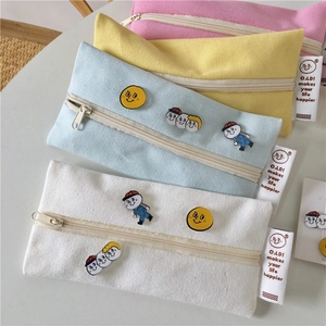 Detail of four colorful canvas pencil cases with cartoon badges and zippers