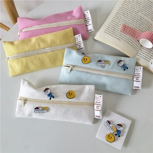 Flat lay of macaron canvas pencil cases with cute embroidery and cartoon pins