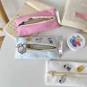 Close-up of pastel canvas pencil cases with cute badges and smooth zippers on a desk