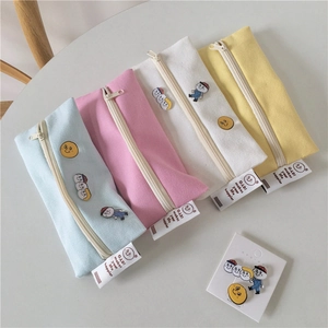 Set of four pastel canvas pencil cases with cute badges in blue, pink, white, and yellow