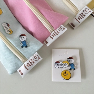 Detail view of canvas pencil cases in macaron colors with cute decorative enamel pins