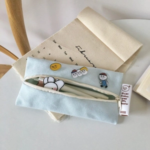 Detail of light blue canvas pencil case featuring retro cartoon embroidery and zipper closure