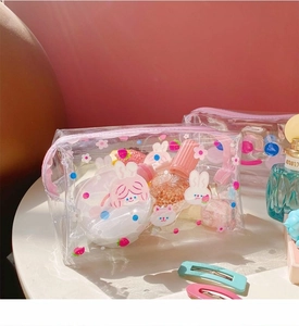 Detail of cute transparent PVC makeup bag featuring rabbit and strawberry patterns