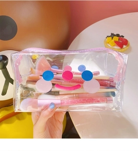 Close-up of cute transparent PVC makeup bag with pink zipper and abstract smile pattern