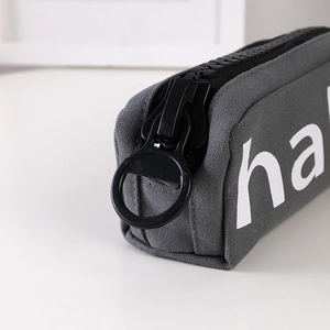 Detail of grey canvas pencil case with chunky black oversized zipper and white logo