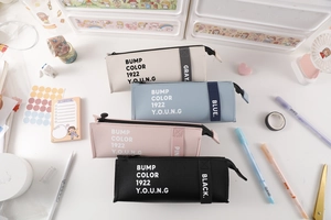 Detailed top view of minimalist PU leather pencil cases in four pastel colors on a desk