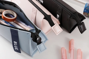 Detailed close-up of textured PU leather pencil cases with zip closure and color labels