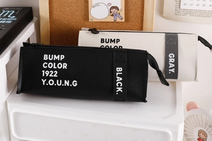 Close-up of large PU leather pencil cases in black and cream on a desk organizer