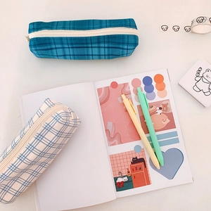 Minimalist navy and light blue plaid pencil cases on desk with stationery items