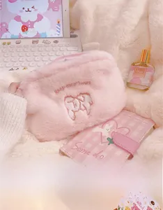 Macro detail of plush pink cosmetic bag featuring cute embroidery and soft fluffy texture
