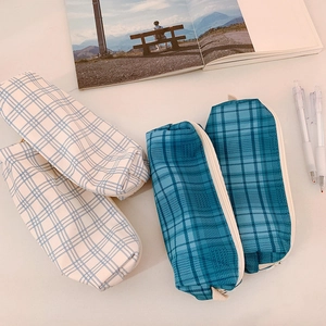 Minimalist plaid canvas pencil cases in blue and white on a clean office desk setup